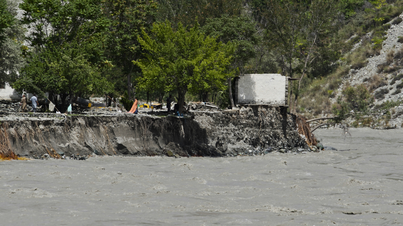 Flash flood damage in Gilgit Baltistan 2025 blocking the Hunza River, showing severe riverbank erosion, collapsed land, and disrupted water flow due to climate change impacts.